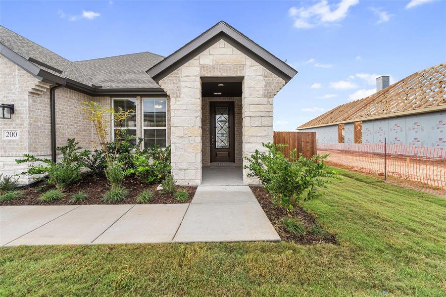 Entrance to property featuring stone siding, a shingled roof, and brick siding Entrance to property featuring stone siding, a shingled roof, and brick siding