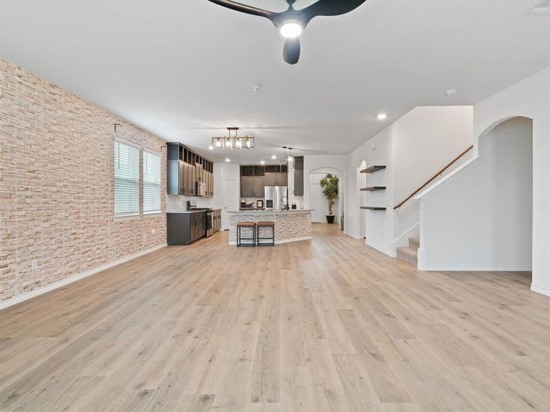 Unfurnished living room with light hardwood / wood-style floors and brick wall