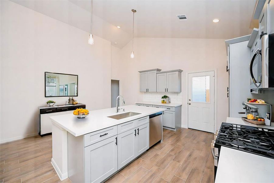 Modern kitchen with high ceilings, sleek cabinetry, and spacious island, perfect for entertaining. Enjoy stainless steel appliances and abundant natural light.