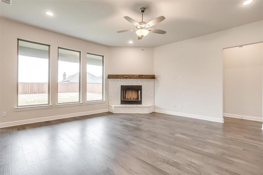 Unfurnished living room featuring a fireplace, ceiling fan, and hardwood / wood-style floors