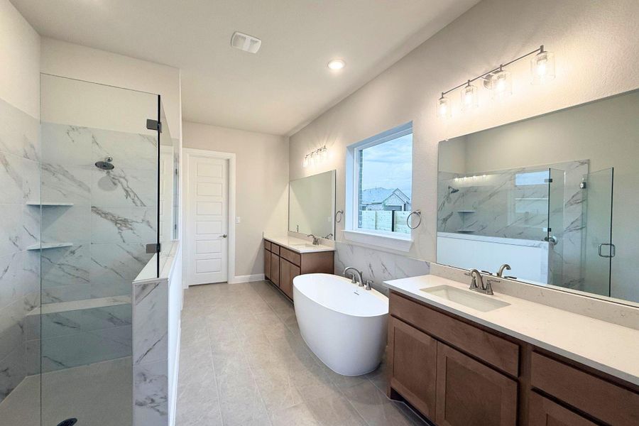 A well-lit primary bathroom provides a spacious walk-in shower and a free-standing soaking tub. A well-lit primary bathroom provides a spacious walk-in shower and a free-standing soaking tub.