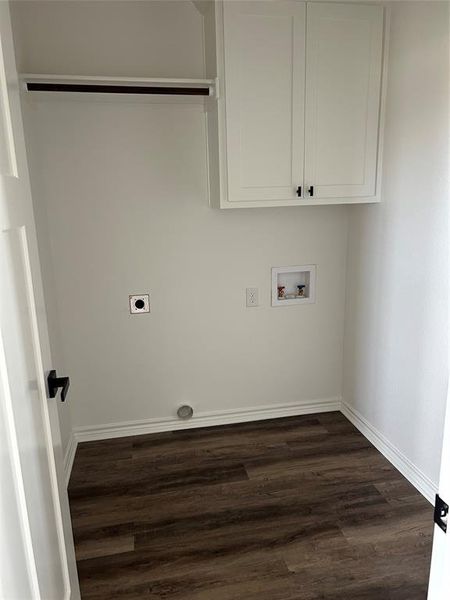 Laundry room with dark wood finished floors, hookup for a washing machine, electric dryer hookup, and cabinet space