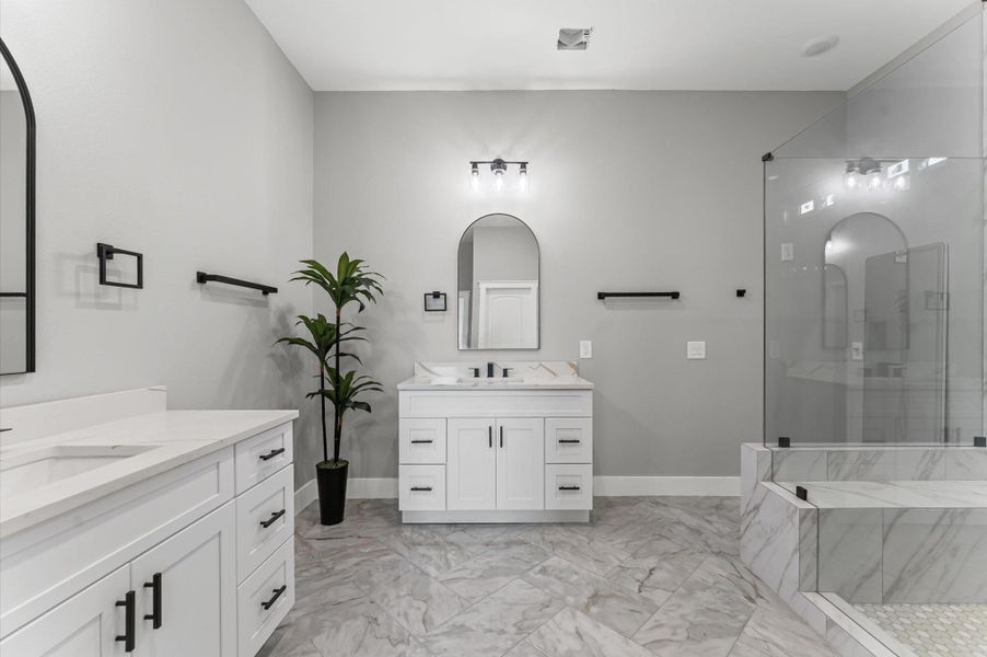Dual vanities with quartz countertops and modern fixtures create a spa-like experience. Dual vanities with quartz countertops and modern fixtures create a spa-like experience.