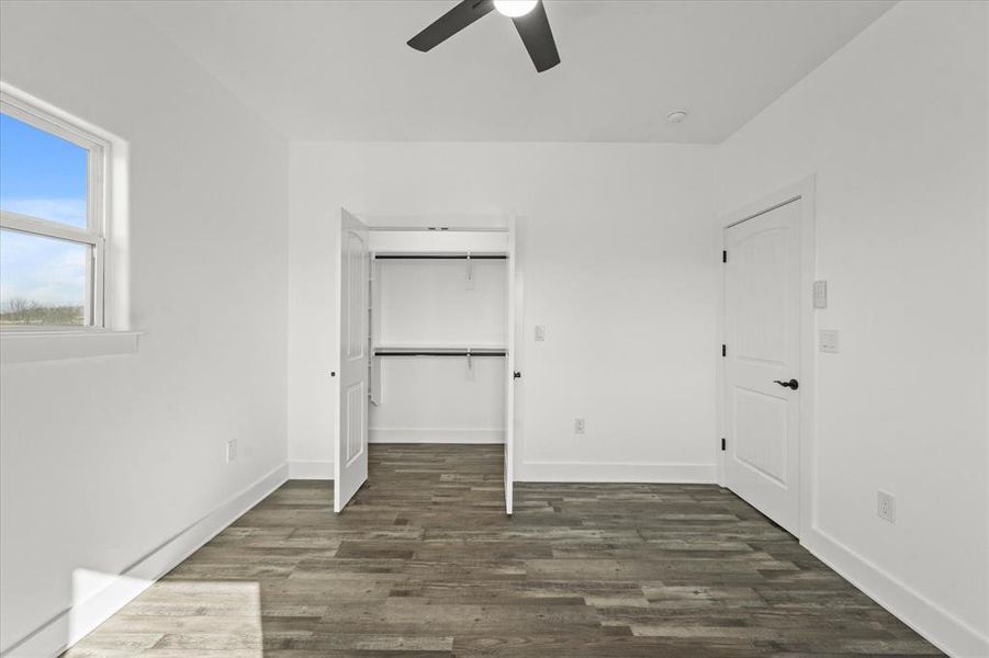 Unfurnished bedroom with dark wood-type flooring, a closet, and ceiling fan