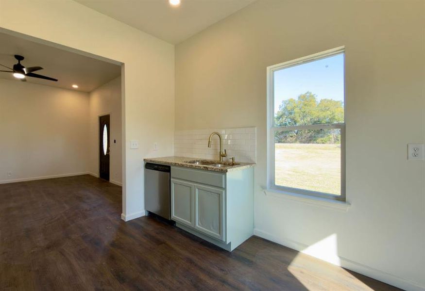 Kitchen featuring decorative backsplash, light stone counters, stainless steel dishwasher, dark wood finished floors, and recessed lighting Kitchen featuring decorative backsplash, light stone counters, stainless steel dishwasher, dark wood finished floors, and recessed lighting