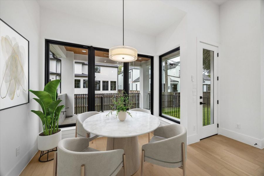 The Breakfast area is a cheerful spot to start or end the day. Large windows join it to the wide covered porch outside. (virt. staged)