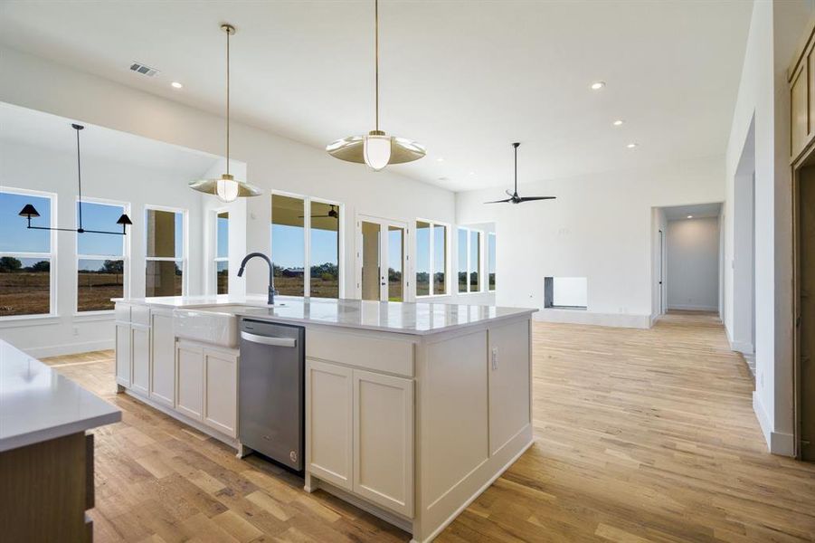 Kitchen with a kitchen island with sink, white cabinets, sink, ceiling fan, and light wood-type flooring