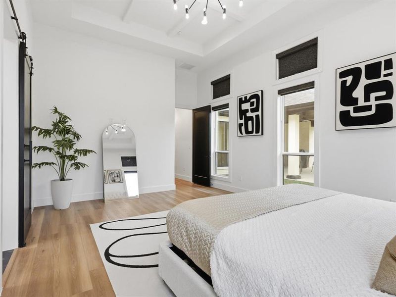 Spacious room featuring wood-finish flooring, a contemporary ceiling light fixture, and multiple windows with black roller shades