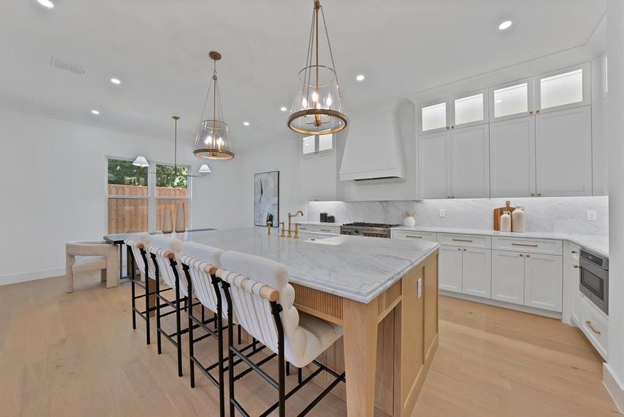 Gourmet kitchen featuring a substantial island with stone countertop, integrated sink, and gold-finish faucet