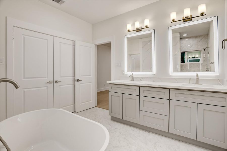 Bright primary bath with luxurious dual illuminated vanities and sleek modern finishes.