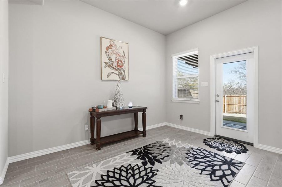 Light gray walls with white trim, wood-finish tile flooring, a window with horizontal blinds, and a glass-paneled door