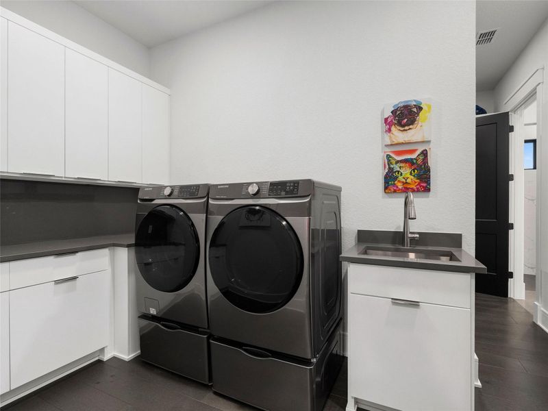 Laundry room with dark wood-style flooring, cabinet space, and separate washer and dryer