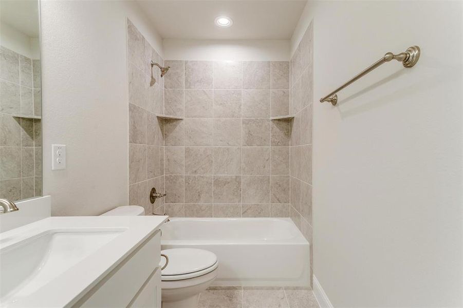 Full bathroom with vanity, tiled shower / bath combo, tile patterned floors, and toilet