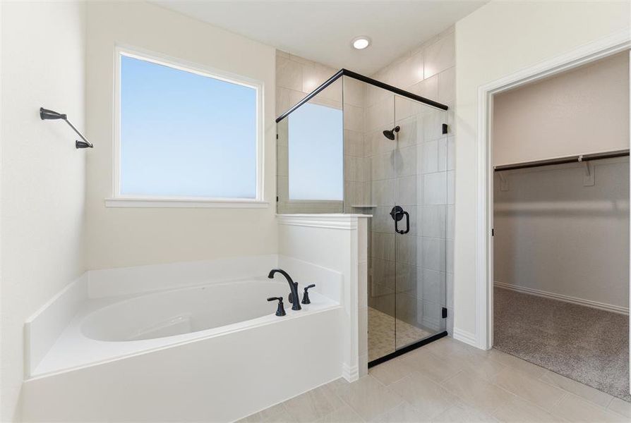 Bathroom featuring a bath, a spacious closet, a shower stall, light tile patterned flooring, and light colored carpet