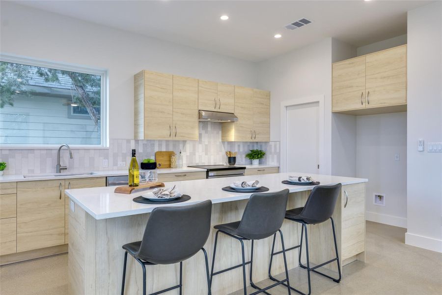 Kitchen has large island and seating, a large pane window over the sink allows natural light to flow into the kitchen.