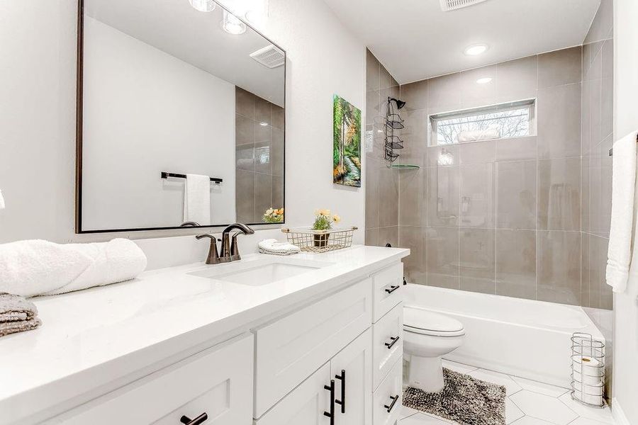 Full bathroom featuring tile patterned floors, vanity, toilet, and tiled shower / bath