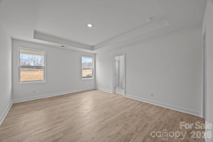 Primary bedroom on first floor with tray ceiling and walk in closet
