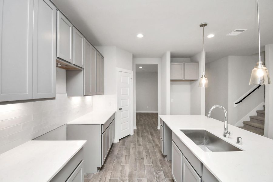 Discover another perspective of this stunning kitchen, generously appointed with an abundance of counter space. Sample photo of completed home with similar floor plan. As-built interior colors and selections may vary.