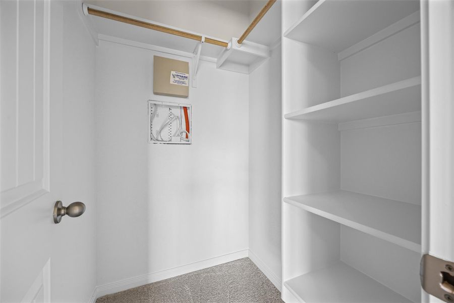 Custom built-in shelving and hanging rods maximize organization in this carpeted walk-in closet. Custom built-in shelving and hanging rods maximize organization in this carpeted walk-in closet.
