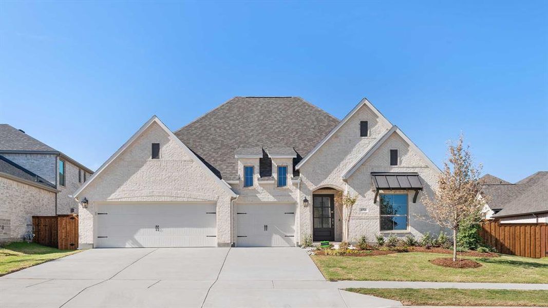 French country style house featuring a front lawn and a garage