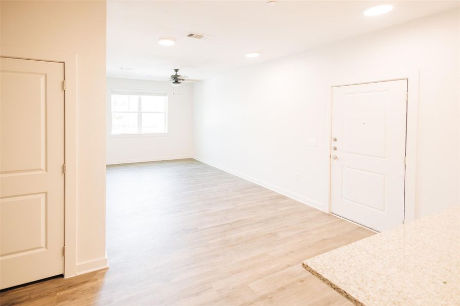 Living room with ceiling fan, light wood-type flooring, and baseboards