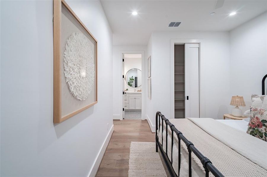 Bedroom featuring a walk in closet, light wood-type flooring, ensuite bath, and a closet