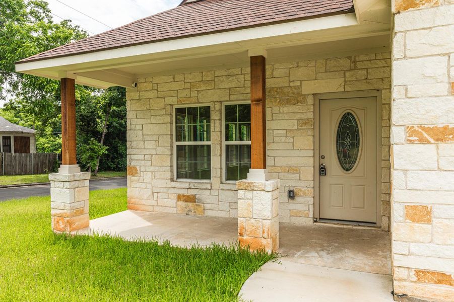 Doorway to property with stone siding and roof with shingles