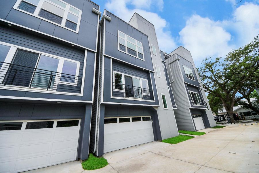 Modern multi-story townhouse with sleek gray facade, large windows, and attached garages. Situated in a well-maintained area with spacious driveways and mature trees nearby. Modern multi-story townhouse with sleek gray facade, large windows, and attached garages. Situated in a well-maintained area with spacious driveways and mature trees nearby.