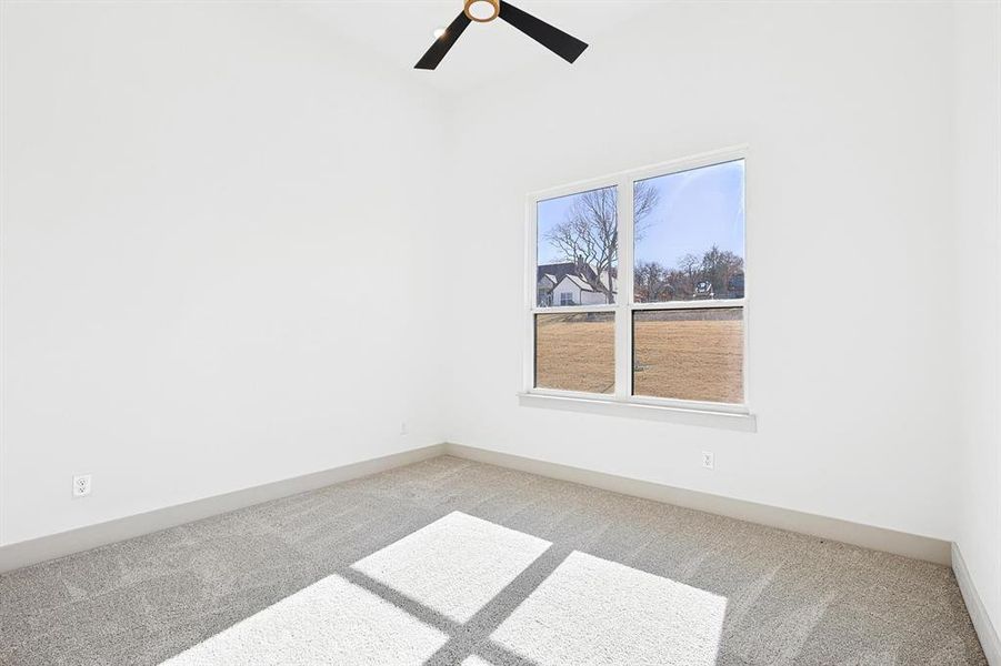 Carpeted spare room with baseboards and ceiling fan Carpeted spare room with baseboards and ceiling fan