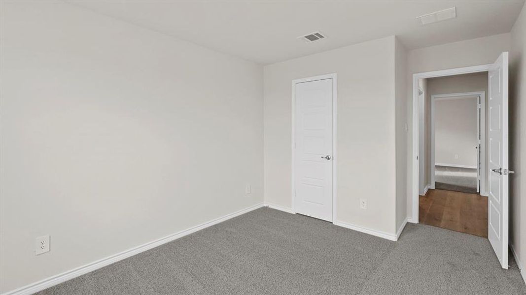 Carpeted room with light neutral wall tones and white baseboards