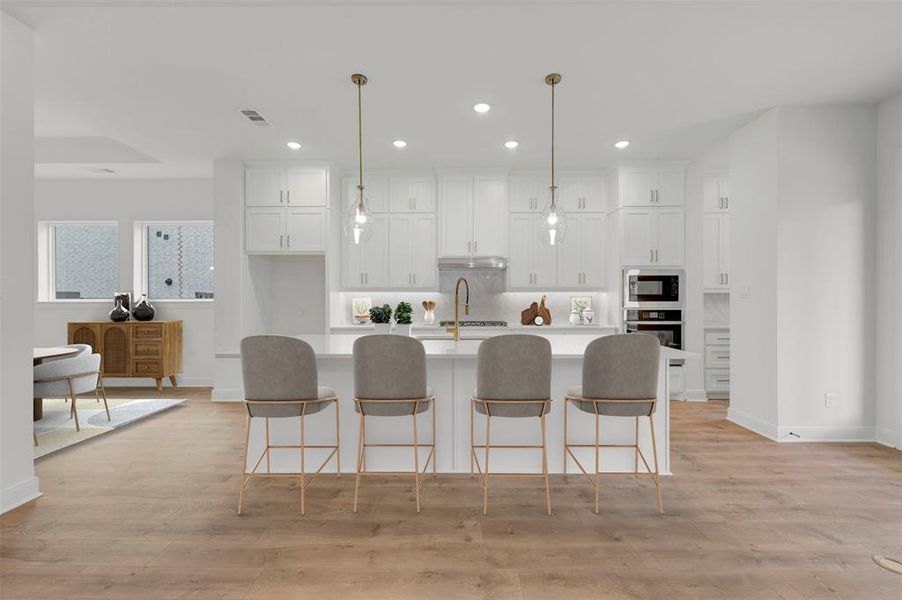 The kitchen features white cabinetry, a kitchen island with seating for four, and hardwood flooring