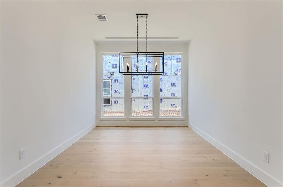 Unfurnished dining area with a notable chandelier and light hardwood / wood-style flooring