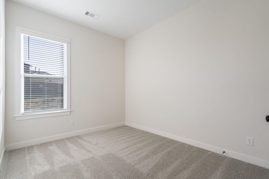 Neutral wall paint, window with white blinds, and light-toned patterned carpet