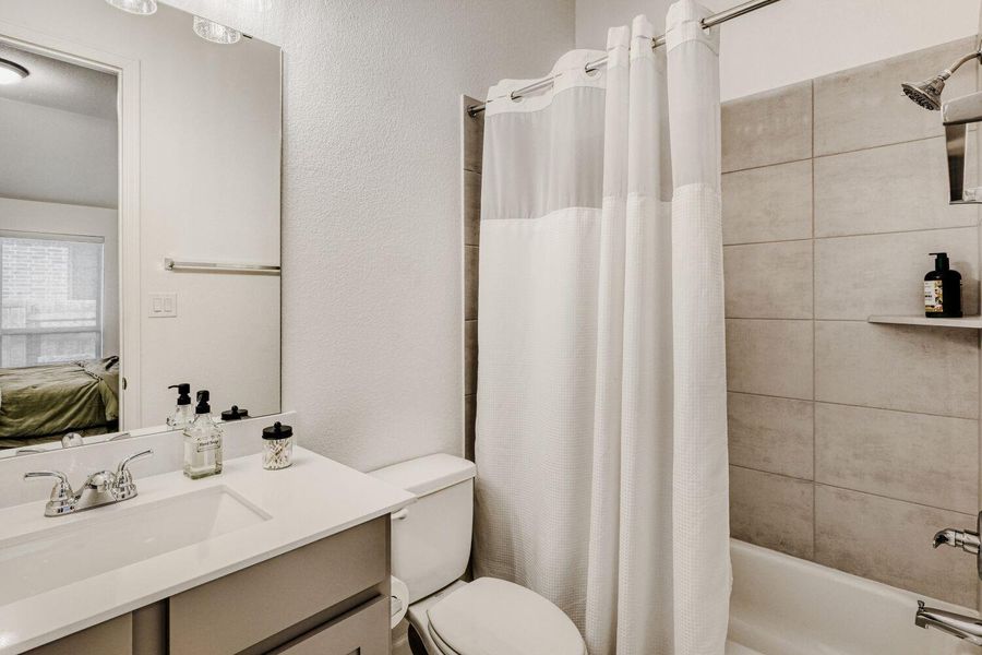 Bathroom with vanity, ensuite bathroom, shower / tub combo, and a textured wall