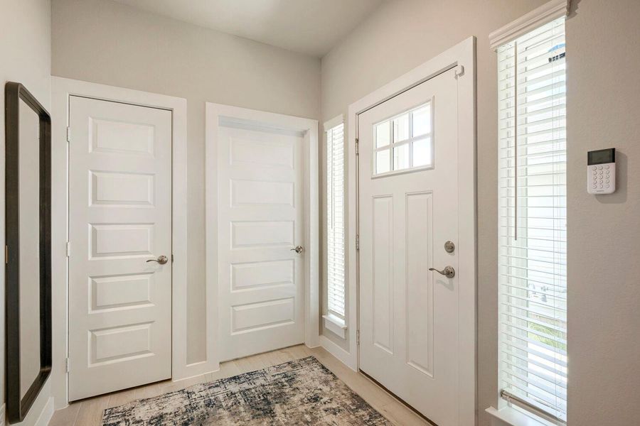 A welcoming entryway with a pristine white front door, sidelight, and light wood flooring. A welcoming entryway with a pristine white front door, sidelight, and light wood flooring.