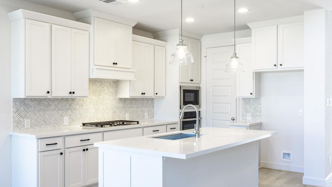 Kitchen with tasteful backsplash, a center island with sink, recessed lighting, light stone counters, and decorative light fixtures Kitchen with tasteful backsplash, a center island with sink, recessed lighting, light stone counters, and decorative light fixtures