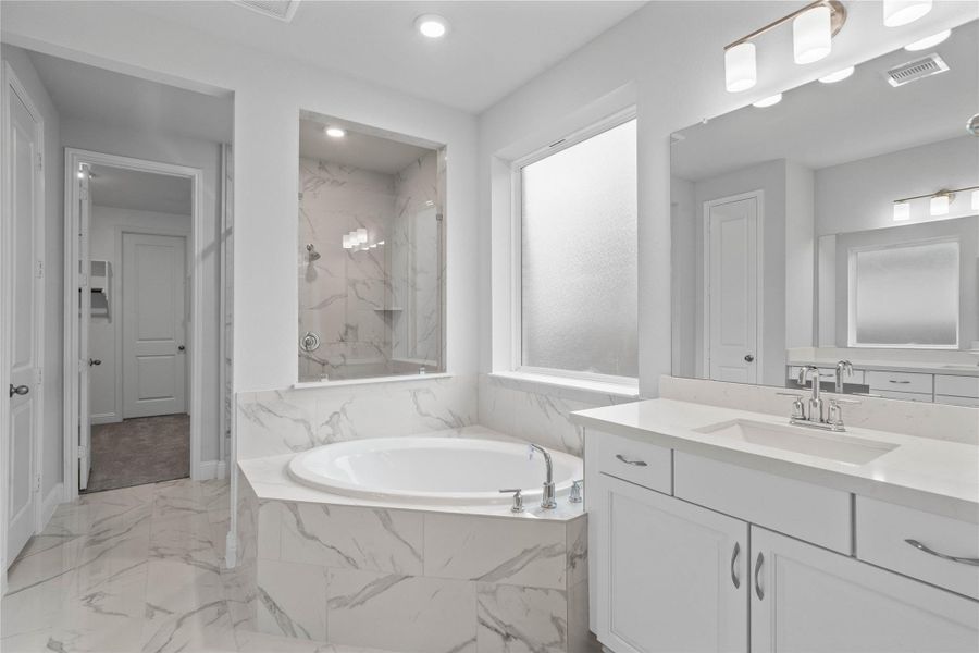 The centerpiece of this contemporary primary bath is the deep, freestanding bathtub, offering an ideal spot for relaxation with a unique view into the walk-in shower.