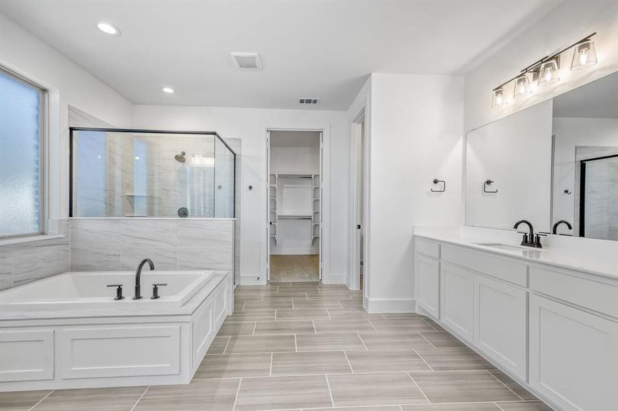 Full bath featuring a shower stall, a garden tub, vanity, a walk in closet, and recessed lighting