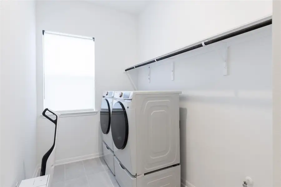 Washroom featuring washing machine and clothes dryer and light tile patterned floors