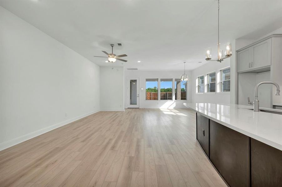 Kitchen featuring open floor plan, light wood finished floors, hanging lights, ceiling fan, and dark wood finish cabinets Kitchen featuring open floor plan, light wood finished floors, hanging lights, ceiling fan, and dark wood finish cabinets