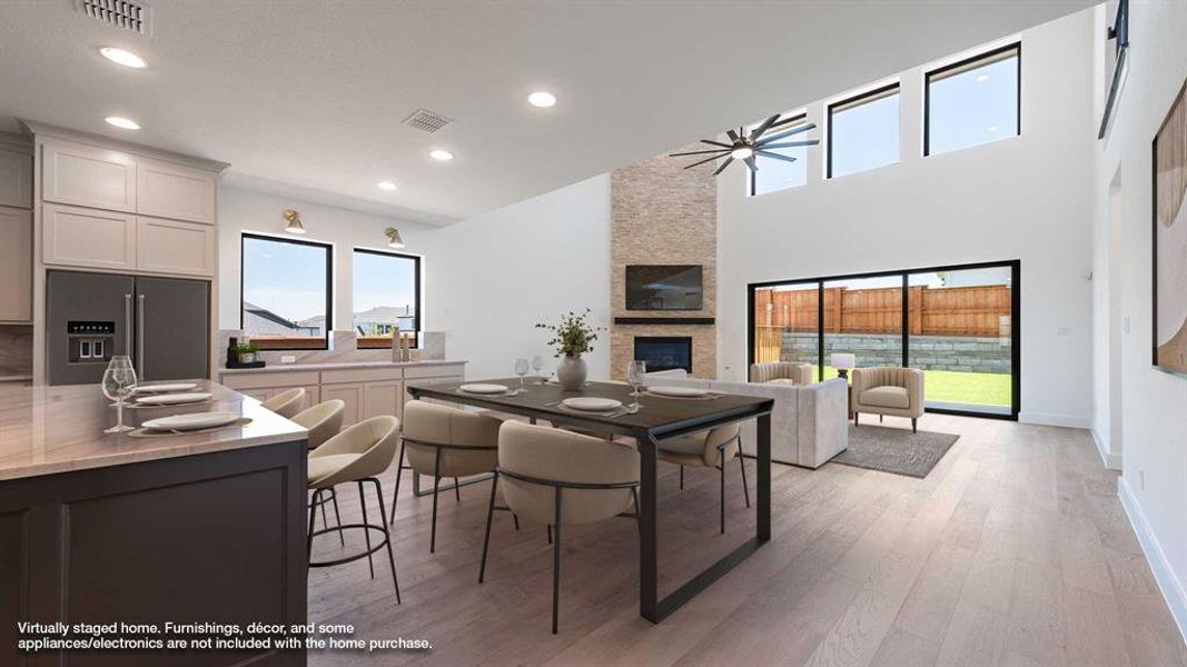 Dining area with a ceiling fan, healthy amount of natural light, a fireplace, light wood finished floors, and recessed lighting