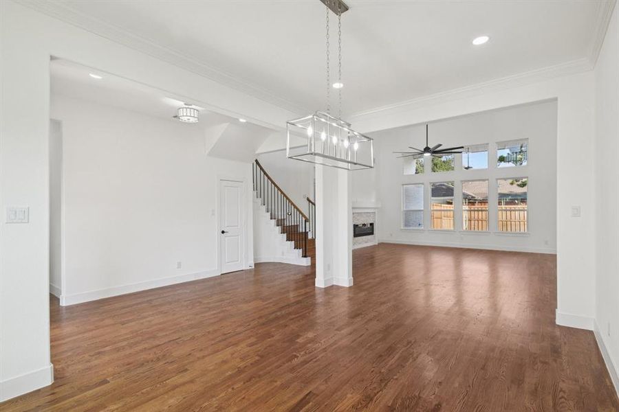 Unfurnished living room with real-wood flooring, a fireplace, crown molding, recessed lighting, and a ceiling fan