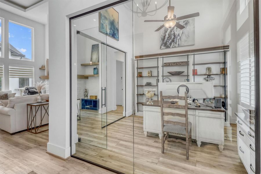 Glass-enclosed office provides excellent sound barrier. Plantation shutters offer privacy, and a transom window above adds natural light. High ceiling with ceiling fan, 8-inch baseboards, and wide plank flooring provide a seamless transition with the rest of the home. This is not just any corner office!
