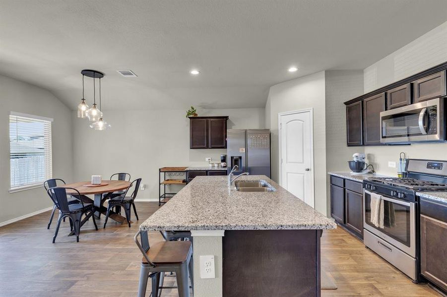 Well-equipped kitchen showcasing a 4-burner gas cooktop, stainless steel oven, and microwave for efficient meal preparation. The walk-in pantry offers ample storage for all your essentials, while the adjacent eating area creates a cozy space for casual dining, making this kitchen both functional and inviting.