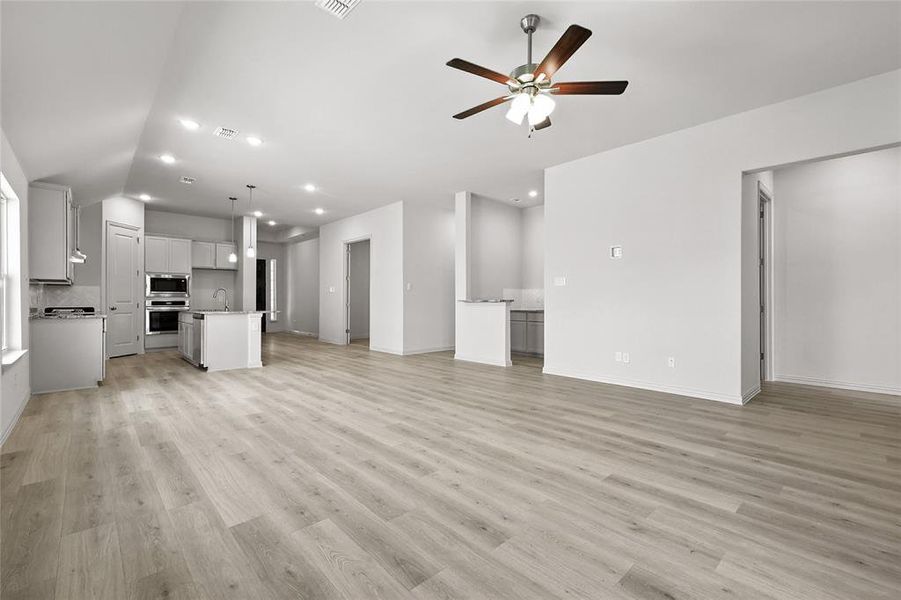 Unfurnished living room featuring ceiling fan, light wood-type flooring, recessed lighting, and vaulted ceiling Unfurnished living room featuring ceiling fan, light wood-type flooring, recessed lighting, and vaulted ceiling