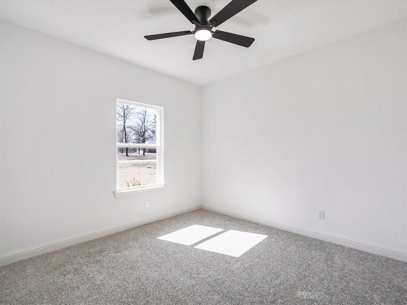 Carpeted spare room featuring baseboards and ceiling fan