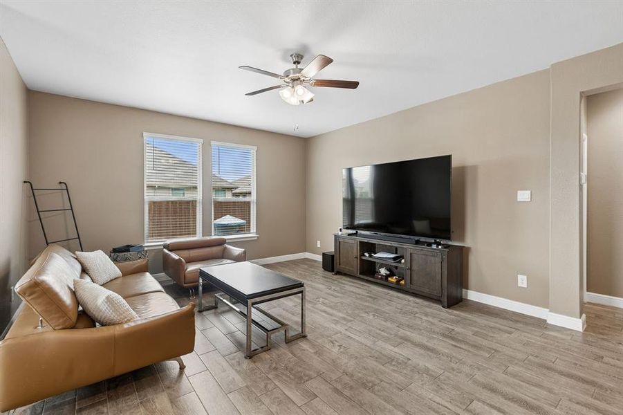 Spacious living area featuring wood-look tile flooring, light neutral wall tones, and recessed lighting