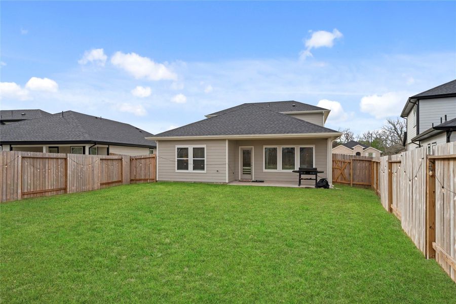 Spacious backyard with a large grassy lawn, covered patio, and full privacy fencing—perfect for outdoor living and entertaining. Spacious backyard with a large grassy lawn, covered patio, and full privacy fencing—perfect for outdoor living and entertaining.