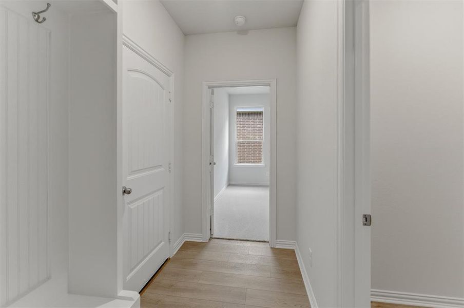 Entryway featuring wood-finish flooring, white trim, and a built-in coat rack
