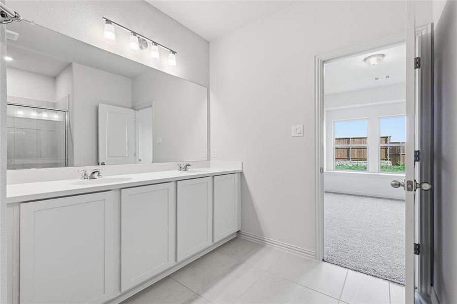 Dual vanity with white cabinetry and integrated sinks set beneath a large mirror with overhead lighting